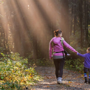 woman and child walking on forest path